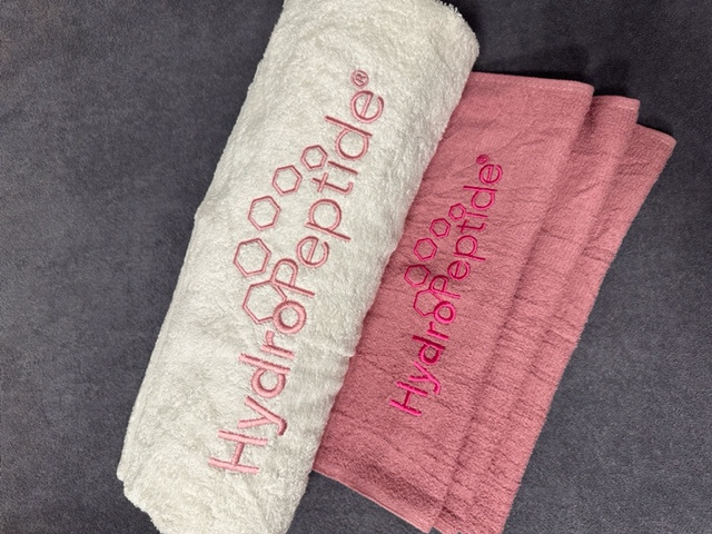 Towel Hydropeptide big white + pink HP sign 90x150 cm<br>Veľká bavlnená osuška Hydropeptide s ružovou výšivkou